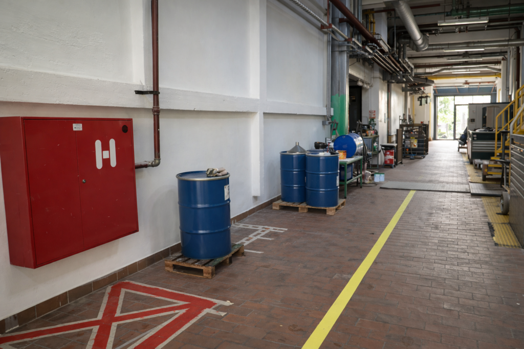 Industrijski prostor z označenimi talnimi linijami in pobarvanimi stenami – industrijska pleskarska dela